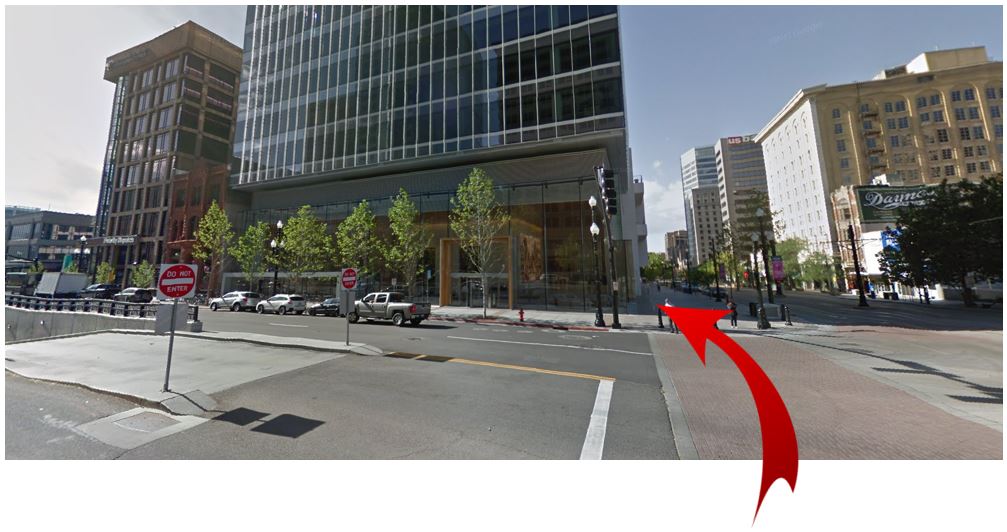 A street view photo looking across 100 South Street toward a tall building on the corner.  A red arrow shows the walking path to get to the building.  The text over the photo says "From City Creek parking, cross 100 South to our large glass lobby."