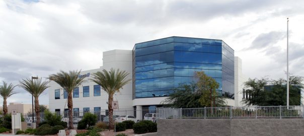 Outside view of Pama Lane industrial building showing glass front, palm trees in front of cloudy sky